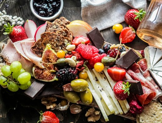 Plank met kaas en charcuterie naast wijn